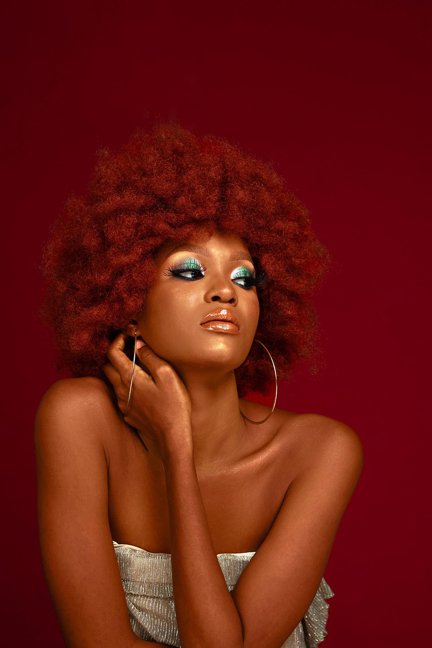 A women with red hair, large hoops earrings with a red background