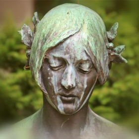Image of the face of a woman statue made from copper.